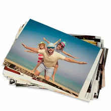 Pilha de revelações de fotos 10x15 da Loja Kiwy com imagem de família feliz na praia.